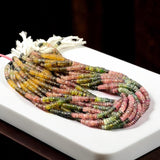 Natural Tourmaline faceted Heishi bead strands displayed on white prop against black background
