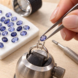 Faceted oval iolite stone being placed into a silver ring setting with tweezers during the jewelry-making process
