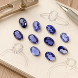 10 Pieces of oval iolite cut stones arranged on jewelry design sketches for rings, earrings and custom jewelry