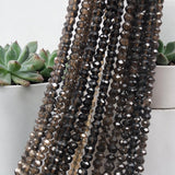 Shaded brown smoky quartz bead strands displayed beside a small green succulent