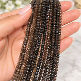 Natural smoky quartz micro-faceted rondelle bead strands displayed in a woman's hand